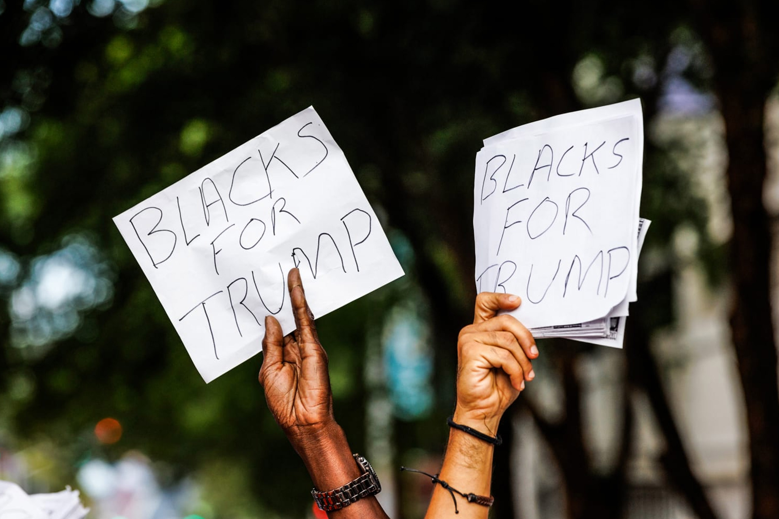 African-American voters hold up homemade signs reading "Blacks for Trump"